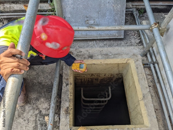 Obraz Worker and safety officer take data for gas test before confine space activity. The photo is suitable to use for industrial background and construction content media.