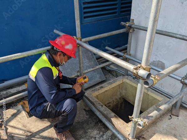 Obraz Worker and safety officer take data for gas test before confine space activity. The photo is suitable to use for industrial background and construction content media.