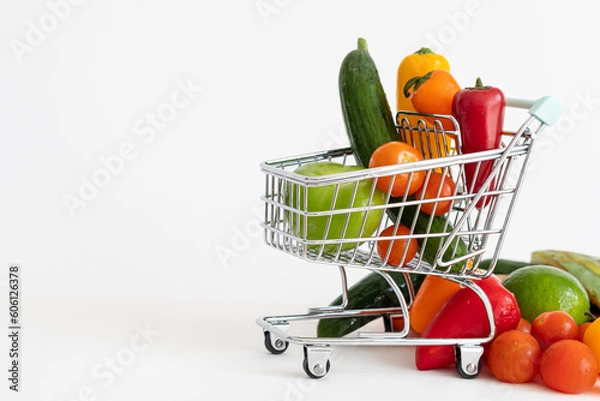 Fototapeta Shopping cart full of vegetables. Vegan food, healthy diet. White background, copy space.