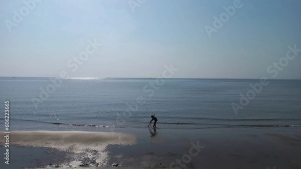 Obraz Coastal Charm: Captivating Beach with Fisherman for Sale on Adobe Stock