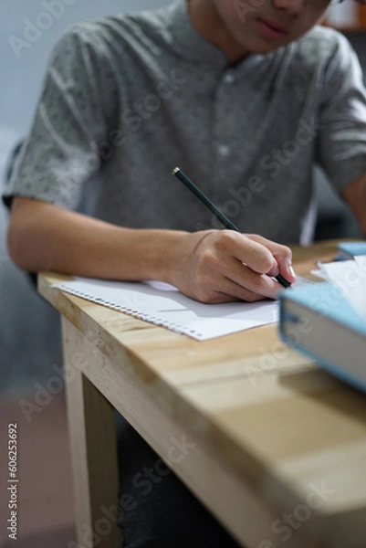 Fototapeta Man writing on a paper while studying, working, or take exam