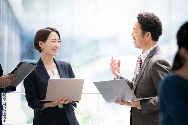 Fototapeta 逆光がきれいなオフィスビルの会社で社長や責任者が部下と話す様子のビジネスシーン　エクゼクティブな人材風　