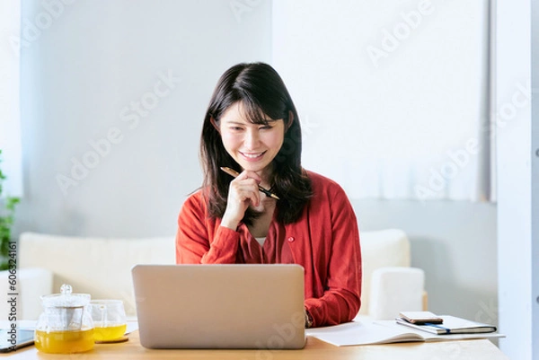 Obraz 自宅のリビングでノートパソコンを使って勉強をする大学生の女性