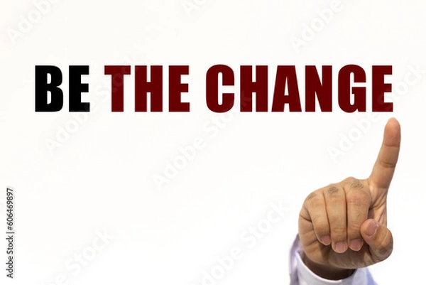 Fototapeta Be the change text on white wall background with businessman's finger point at the message with empty space. This message can be used as business concept about being the change.