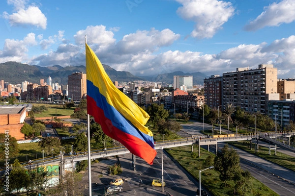 Fototapeta Photo of the Colombian flag on a pole with avenue and city buildings in the background. Bogotá. Colombia.