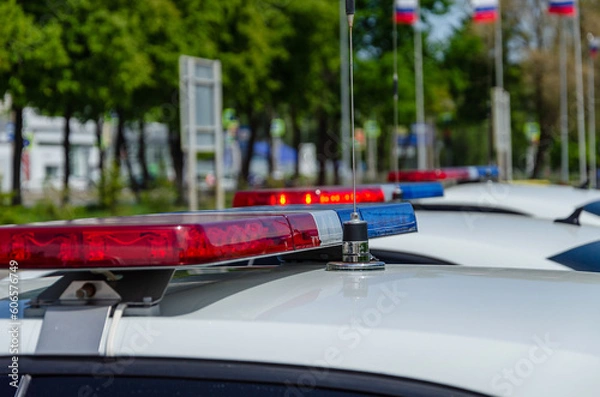 Obraz Police car flashing light. In the background, the flags of Russia are out of focus.