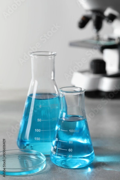 Fototapeta Different laboratory glassware with light blue liquid on table
