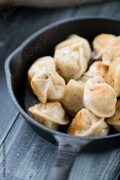 Fototapeta Vertical shot of roasted pelmeni in a cast-iron pan, close-up