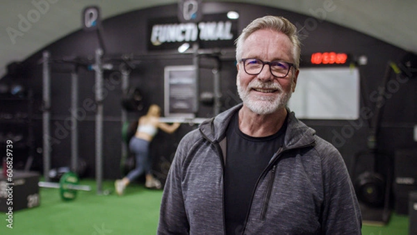 Fototapeta Portrait of senior active male in the gym smiling to camera, with space for text