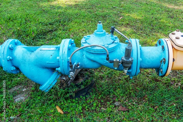 Obraz Close-Up View of a Gate Valve in a Piping System Amidst a Lush Grassy Field - Efficient Fluid Control Solutions