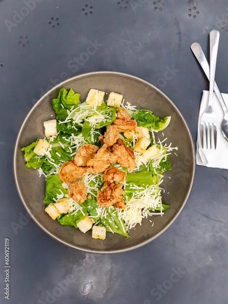 Fototapeta Mix fresh leaves of arugula, lettuce, spinach, slices deep fried chicken for salad on a black table background. Selective focus. 