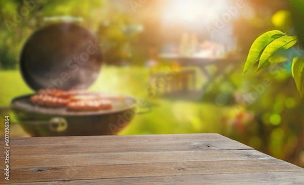 Fototapeta summer time in backyard garden with grill BBQ, wooden table, blurred background