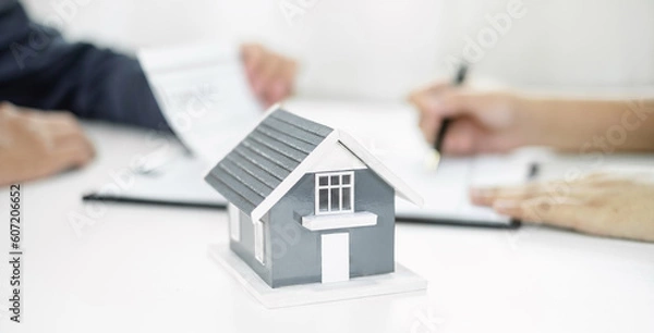 Fototapeta A real estate agent with a home model is talking to clients about renting a house and buying home insurance and contracting the contract after the formal negotiation is completed