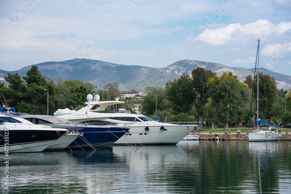 Fototapeta Luxury modern yachts in marina with a beautiful view of the mountains and reflection in calm water. Vacation and tourism concept 