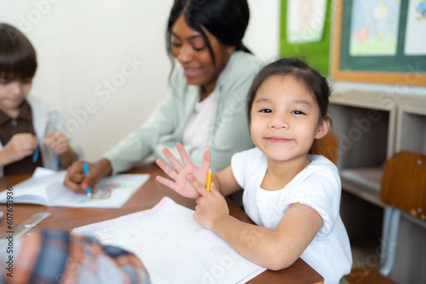Fototapeta Portrait of little girl study art in classroom at school. She looking to camera and smile.