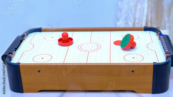 Fototapeta The plot shot of an air hockey game on a table Portable table hockey includes plastic hockey blades, a mini puck and goalkeepers