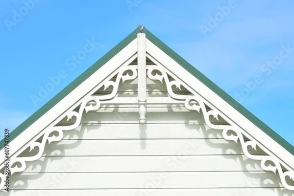Fototapeta Gable end with weatherboard and ornamental fascia under green metal roof.