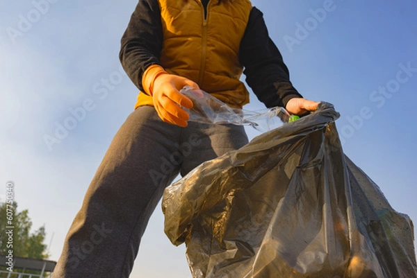 Fototapeta Close-up of male in rubber gloves picking up plastic bottle. Environmental ecology pollution concept. Earth Day.