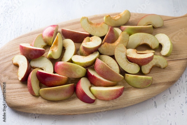 Obraz Wooden board with sliced apples for baking or other dishes on a light blue background