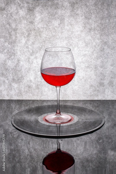 Fototapeta Still life with a glass of red wine on a vinyl record
