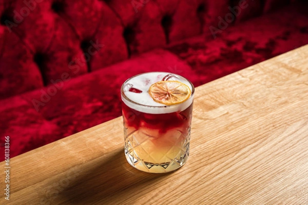 Fototapeta New York sour or Continental sour cocktail with bourbon or whisky garnished with dried lemon wheel at the wooden table at bar or restaurant, horizontal photo