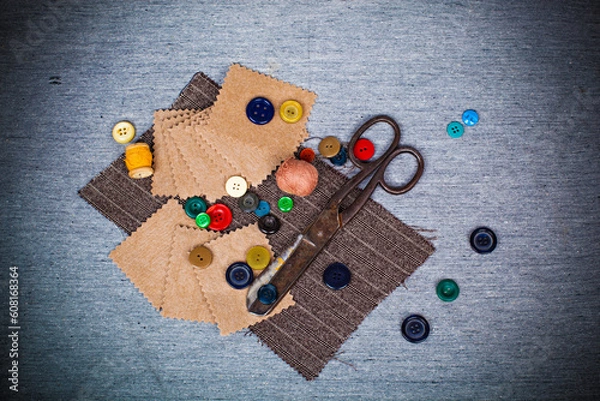 Fototapeta Scissors, threads, buttons, pieces of felt and fabric on a gray background. Needlework abstract background in retro style.