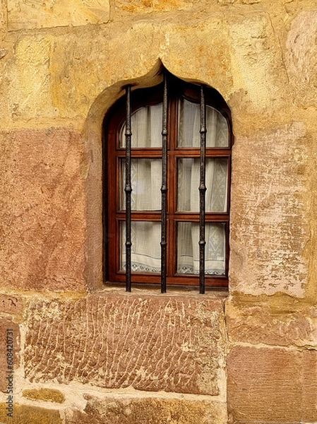 Obraz A beautiful antique window made of modern materials in a stone wall of an old restored house protected by figured decorativel bars