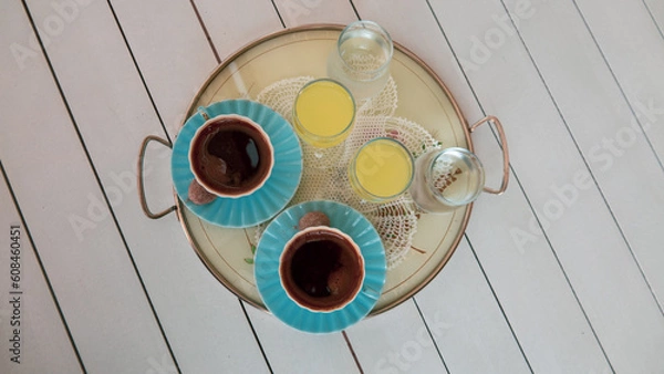 Fototapeta Two cups of turkish coffee served with a little cookie and lemon liqueur or  limoncello  on tray on white wooden table