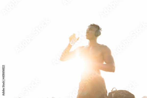 Obraz Young athlete man listening music while resting after training. Handsome African man training outside