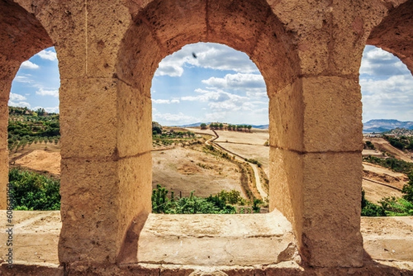 Fototapeta view of a field through an arc at a Sicily ancient town 