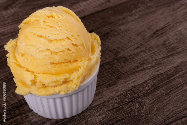 Obraz Yellow ice cream served in a white pot. Tasty traditional yellow gelato enjoyed around the world. Close-up photograph with empty space for text on the right.