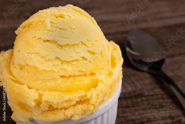 Fototapeta Vanilla ice cream served in a white bowl next to a spoon. Food aligned left background blurred .