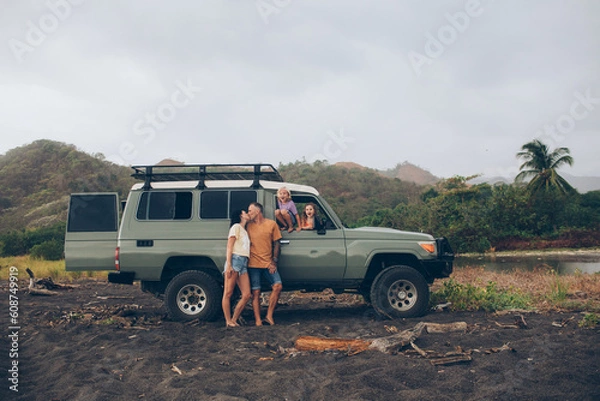 Obraz family laughing and smiling outside of their all terrain vehicle car truck at the beach