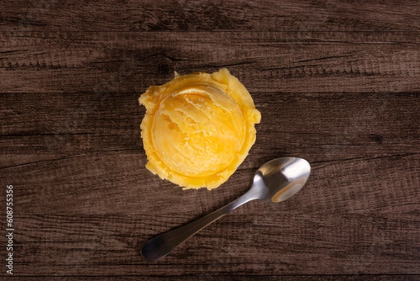 Obraz Tasty yellow ice cream served in a white china pot next to a spoon. Top photography. Ice cream parlors and ice cream parlours.