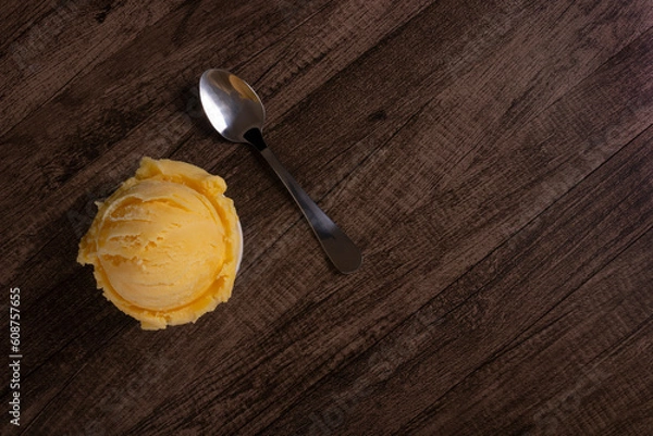 Obraz Tasty yellow cream ice cream served in a white bowl next to a spoon. Top photography with elements aligned on the left and empty space on the right. Ice cream ball.