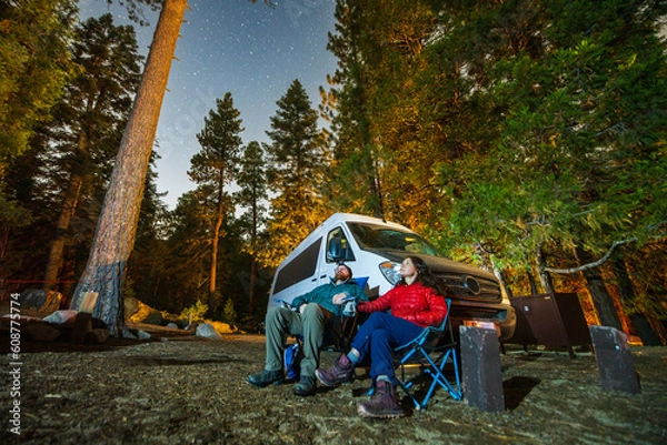Fototapeta Couple gazes at the stars while camping with their van.