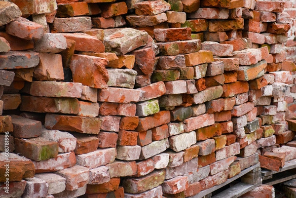 Obraz restoration work. the wall of the old building was dismantled. old moldy bricks lie on wooden pallets
