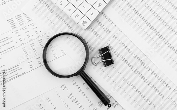 Fototapeta Calculator and magnifying glass on financial statement. Financial, accounting and business concept.