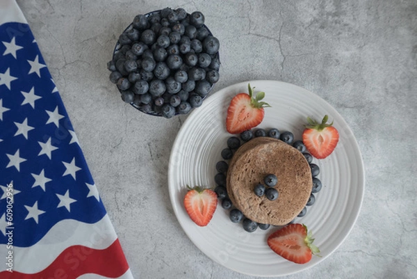 Obraz Pancakes with forest fruits berries on beautiful table. Healthy breakfast. Blueberries and strawberry on pancakes. Independence Day 4th of July. 