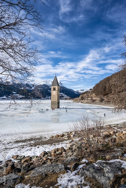 Fototapeta Winter scene at Resia Lake  with sunken gray steeple. Resia Lake is an artificial lake located in the western portion of South Tyrol, Italy, near the Resia Pass.