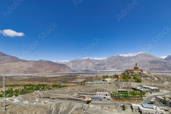 Fototapeta Big Sitting Buddha Statue at Diskit Monastery with Himalaya Range in the back - Nubra Valley, Ladakh, India
