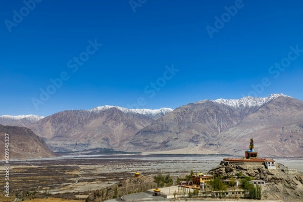 Fototapeta Big Sitting Buddha Statue at Diskit Monastery with Himalaya Range in the back - Nubra Valley, Ladakh, India
