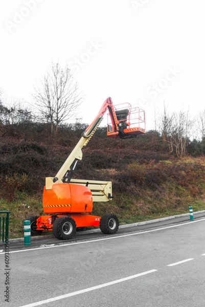 Fototapeta orange and light yellow mobile telescopic crane in on a road on an autumn day, Crane to do electric post checking operations