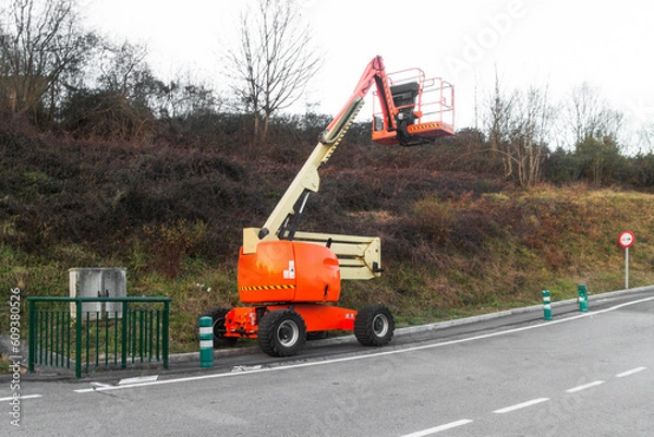 Fototapeta orange and light yellow mobile telescopic crane in the middle of the forest on a winter day, Crane to do power line checking operations