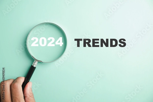 Fototapeta The image features magnifier glasses with the text New Year 2024 Trends, emphasizing the main trend of change. It represents the evaluation methods, popular topics, and new trends in business.