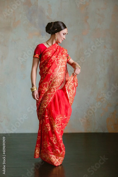 Obraz Pregnant woman in red sari. mehendi. Indian painting on woman's hands and pregnant belly with henna tattoo on room background