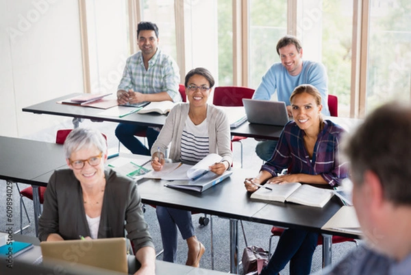Fototapeta Smiling students watching teacher in adult education classroom