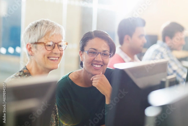 Obraz Smiling women at computer in adult education classroom