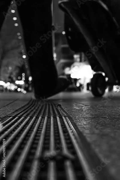 Fototapeta drain in the city with somebody walking over it