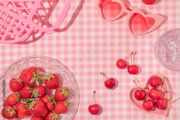 Fototapeta Summer creative layout with strawberries, cherries, glass with ice cubes, heart sunglasses and handbag on pastel pink plaid background. 80s or 90s retro aesthetic idea. Minimal summer fruit idea.